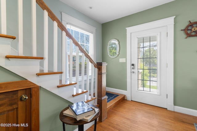 entryway featuring light wood finished floors, baseboards, and stairway