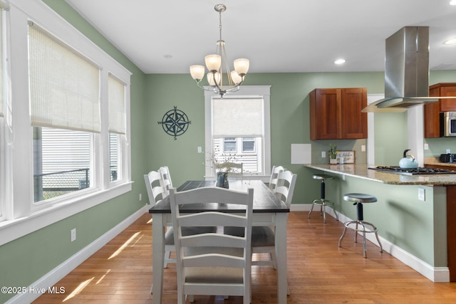 dining room featuring light wood finished floors, a notable chandelier, baseboards, and a healthy amount of sunlight