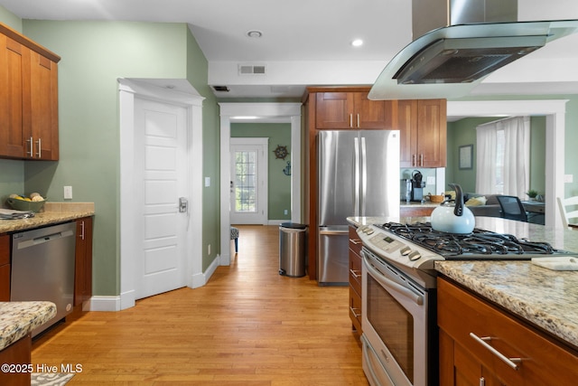 kitchen with light stone counters, light wood-style flooring, visible vents, appliances with stainless steel finishes, and range hood