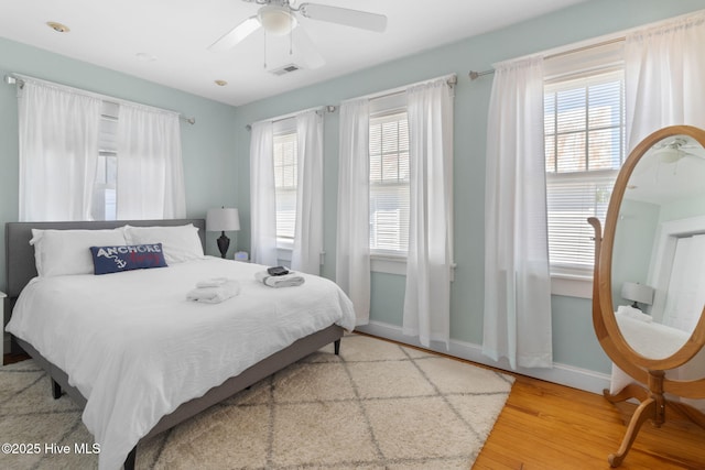 bedroom with visible vents, baseboards, ceiling fan, and wood finished floors