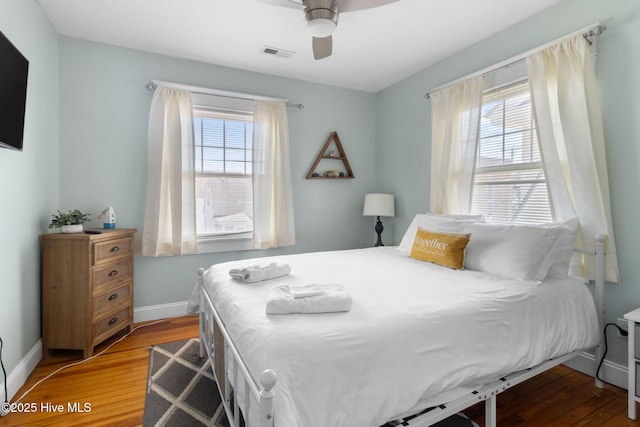 bedroom featuring ceiling fan, visible vents, baseboards, and wood finished floors