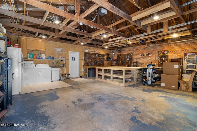 garage featuring a garage door opener, freestanding refrigerator, a workshop area, and washing machine and dryer