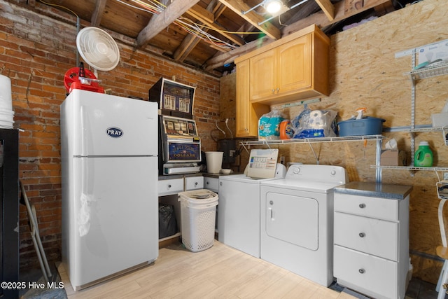 laundry room featuring brick wall, light wood finished floors, and independent washer and dryer