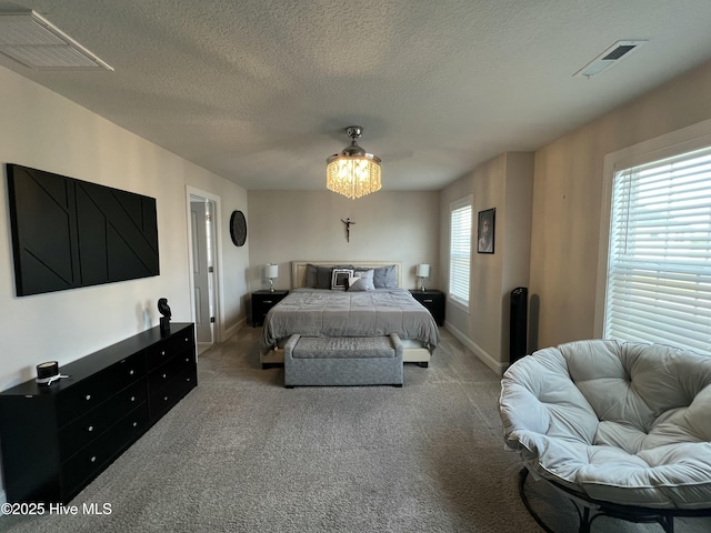 bedroom featuring a textured ceiling, carpet flooring, baseboards, and visible vents