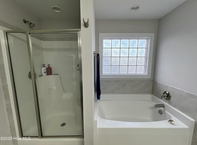 bathroom featuring a shower stall and a garden tub