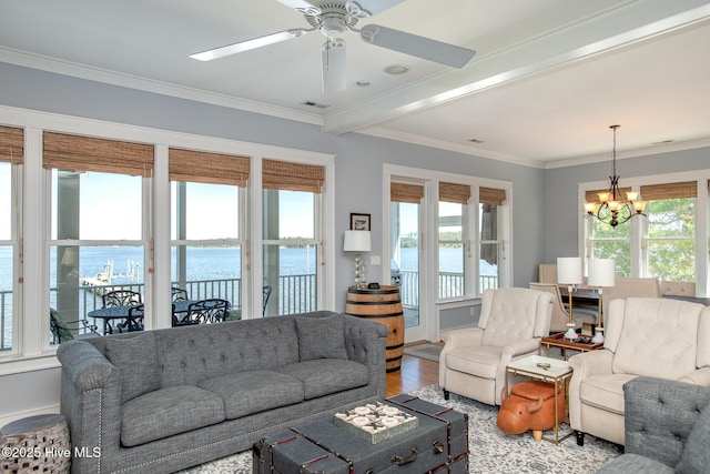 living area with crown molding, a water view, wood finished floors, and ceiling fan with notable chandelier