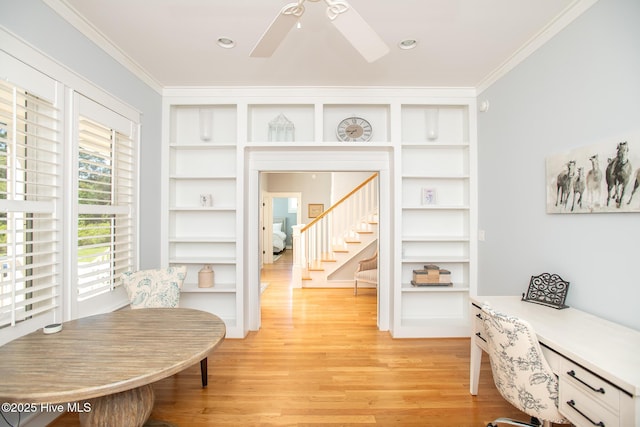 interior space featuring ornamental molding, light wood-style flooring, a ceiling fan, and built in shelves