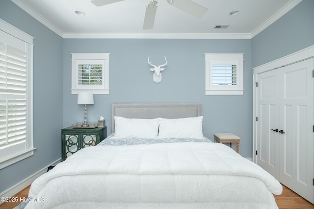 bedroom featuring crown molding, multiple windows, wood finished floors, and visible vents