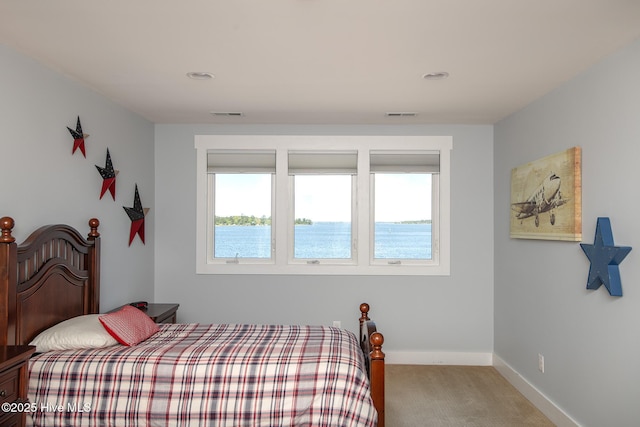 bedroom with a water view, baseboards, visible vents, and light carpet