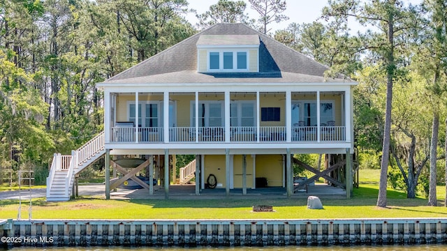 back of property with a fire pit, stairs, a shingled roof, a sunroom, and a lawn