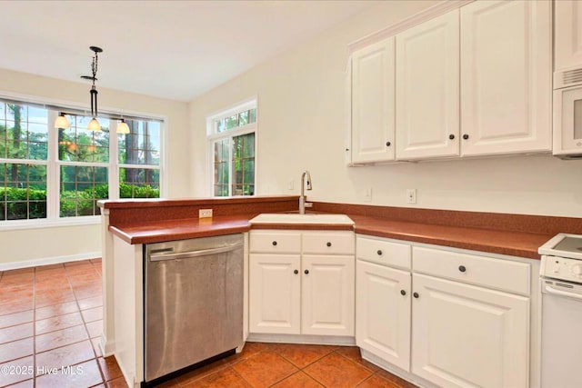 154 Windsor Cir SW, Ocean Isle Beach, NC 28469 - kitchen featuring white appliances, a sink, dark countertops, light tile patterned flooring, and a peninsula