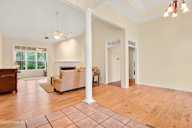 154 Windsor Cir SW, Ocean Isle Beach, NC 28469 - living room with light wood-style flooring, a ceiling fan, a fireplace, decorative columns, and a chandelier