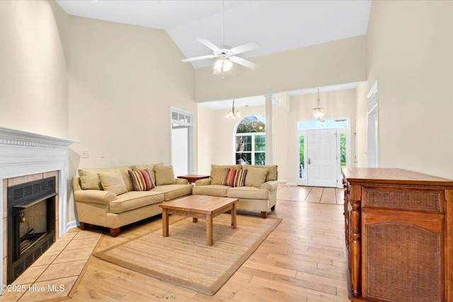 154 Windsor Cir SW, Ocean Isle Beach, NC 28469 - living area featuring a tiled fireplace, light wood-style floors, high vaulted ceiling, a ceiling fan, and a chandelier