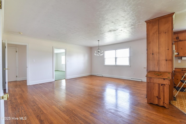 empty room featuring a notable chandelier, baseboards, a textured ceiling, a baseboard radiator, and wood finished floors