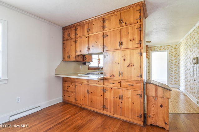 kitchen with baseboard heating, wallpapered walls, ornamental molding, and wood finished floors