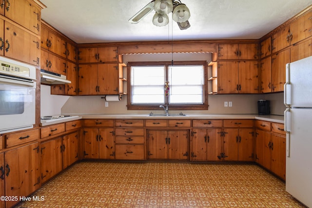kitchen featuring a sink, light countertops, white appliances, and light floors