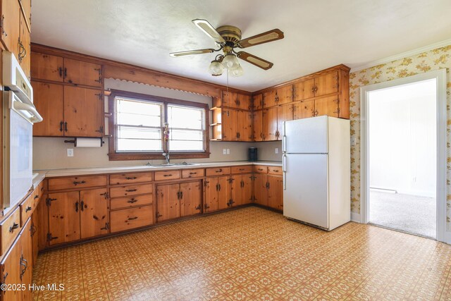 kitchen with light floors, white appliances, light countertops, brown cabinetry, and ceiling fan