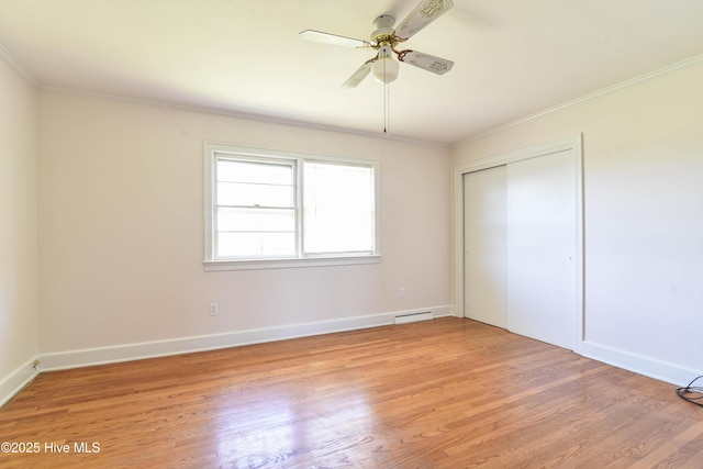 unfurnished bedroom featuring visible vents, a closet, baseboards, crown molding, and light wood-style flooring