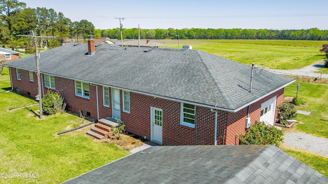 view of front of home with brick siding, a front lawn, a chimney, and a shingled roof