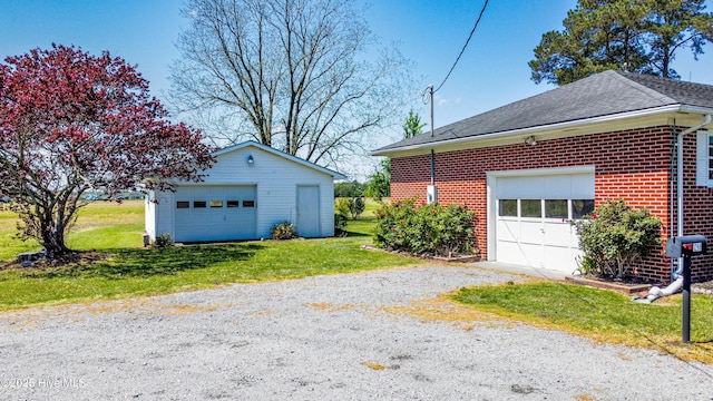 view of side of property with a lawn, a garage, an outdoor structure, and brick siding