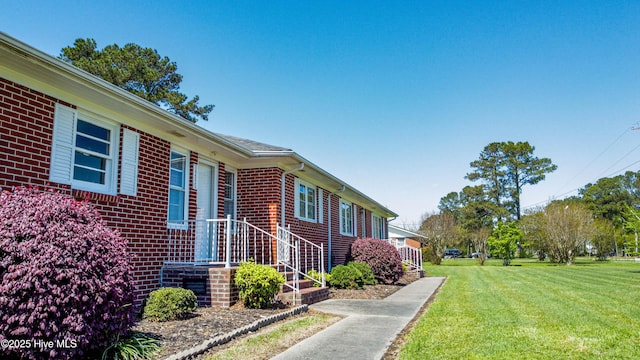 view of side of property with brick siding and a lawn