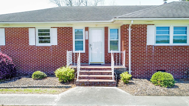 view of front of property with roof with shingles and brick siding