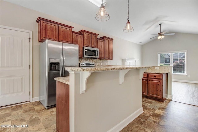 kitchen with ceiling fan, appliances with stainless steel finishes, pendant lighting, a kitchen island, and a breakfast bar area