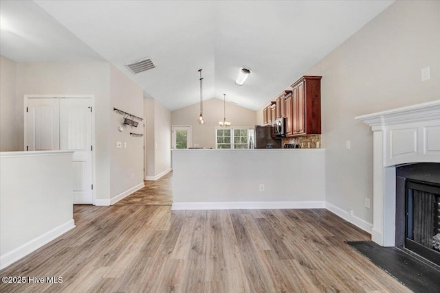 unfurnished living room featuring light wood-type flooring, baseboards, a fireplace with raised hearth, visible vents, and lofted ceiling