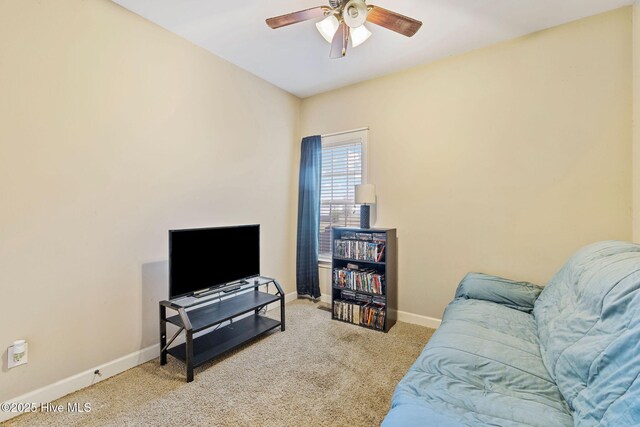 carpeted living area featuring baseboards and a ceiling fan