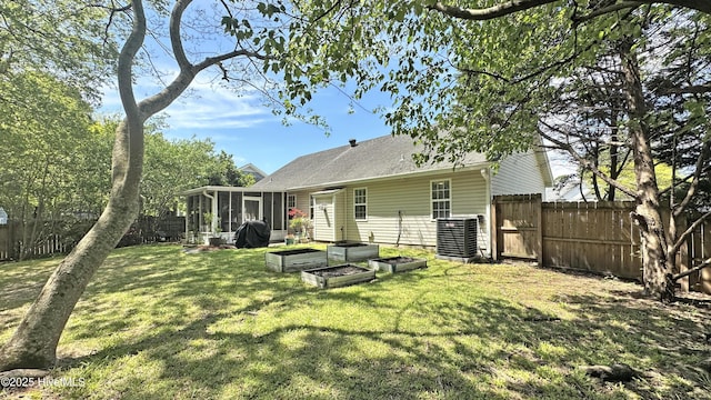 back of property featuring a sunroom, a yard, a garden, and a fenced backyard
