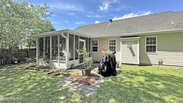 rear view of property with a sunroom, a yard, a shingled roof, and fence