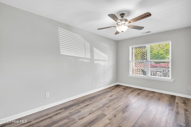 spare room featuring baseboards, wood finished floors, and ceiling fan