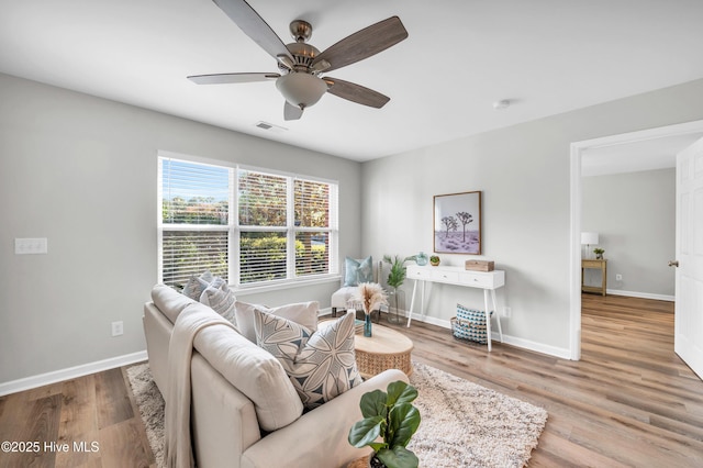 living area featuring baseboards, wood finished floors, and a ceiling fan