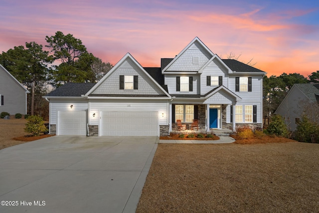 craftsman inspired home featuring an attached garage, stone siding, and driveway