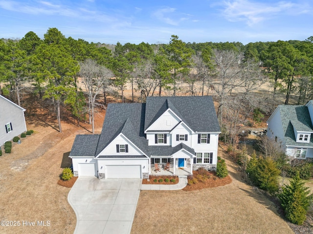 view of front of house with driveway, a shingled roof, and a garage
