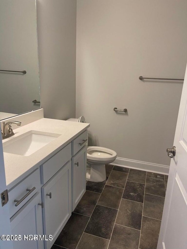 bathroom with vanity, baseboards, and toilet