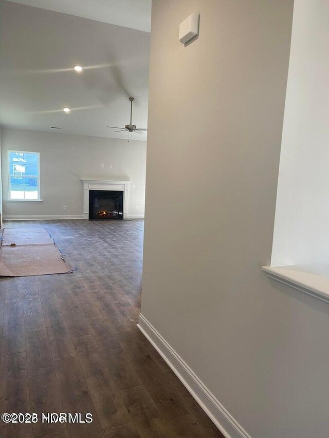 corridor with dark wood-type flooring and baseboards