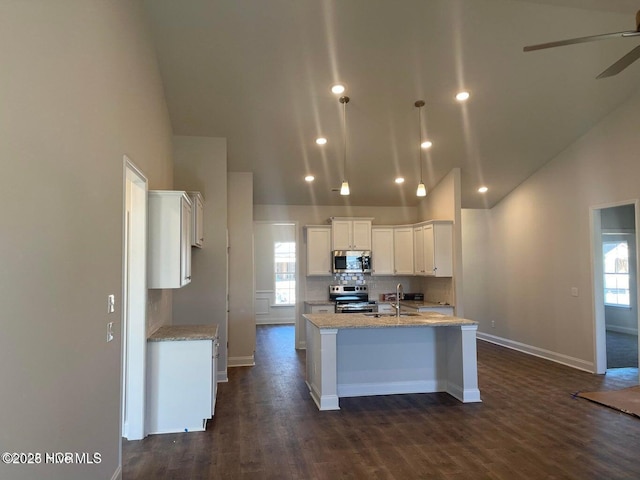 kitchen with a sink, a wealth of natural light, white cabinetry, a center island with sink, and stainless steel appliances