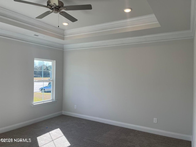 spare room featuring baseboards, a raised ceiling, crown molding, dark carpet, and ceiling fan