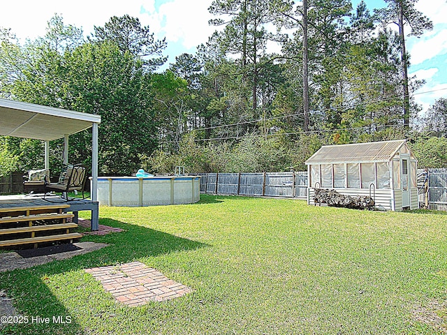 view of yard featuring a deck, an outbuilding, a fenced backyard, and a greenhouse