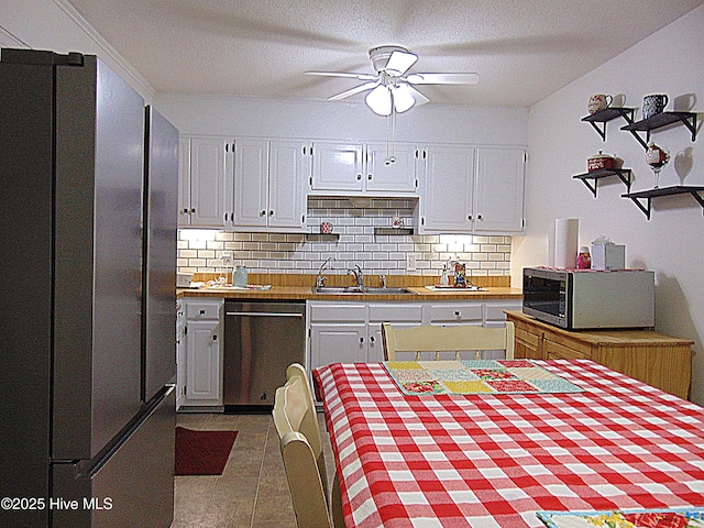 kitchen featuring tasteful backsplash, ceiling fan, freestanding refrigerator, dishwashing machine, and stainless steel microwave