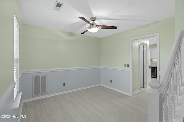 spare room featuring wood finished floors, baseboards, a ceiling fan, and visible vents