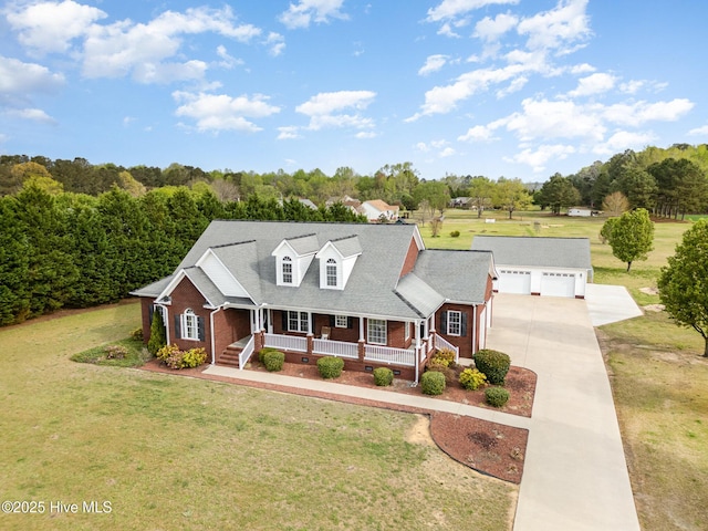 view of front of home featuring covered porch, an outdoor structure, concrete driveway, brick siding, and a front lawn