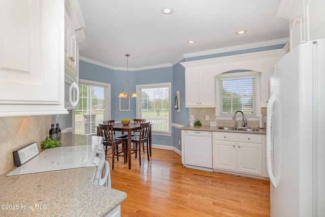 kitchen with a sink, light wood-style flooring, white appliances, and a healthy amount of sunlight