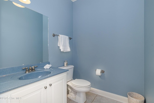 half bathroom featuring toilet, vanity, baseboards, and tile patterned flooring