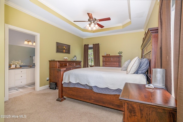 carpeted bedroom with baseboards, ceiling fan, crown molding, a tray ceiling, and ensuite bath