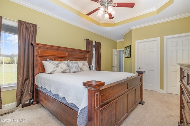 bedroom with baseboards, light carpet, crown molding, visible vents, and a raised ceiling