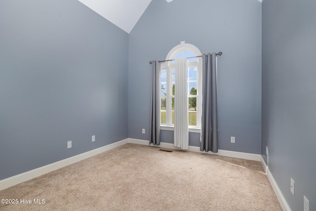 empty room with high vaulted ceiling, carpet flooring, and baseboards