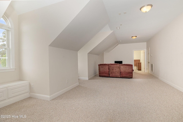 unfurnished bedroom featuring visible vents, multiple windows, carpet flooring, and vaulted ceiling