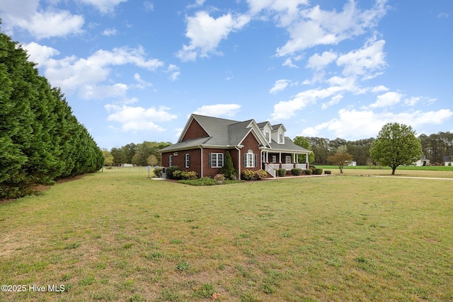 view of front of property with covered porch, a front lawn, and brick siding